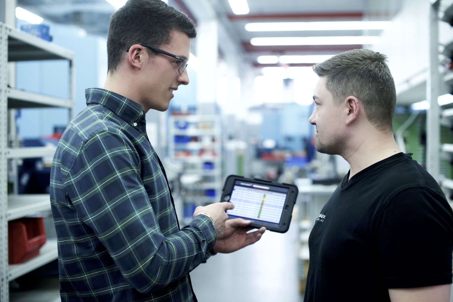 Mitarbeiter unterhalten sich an Tablet in Fertigung