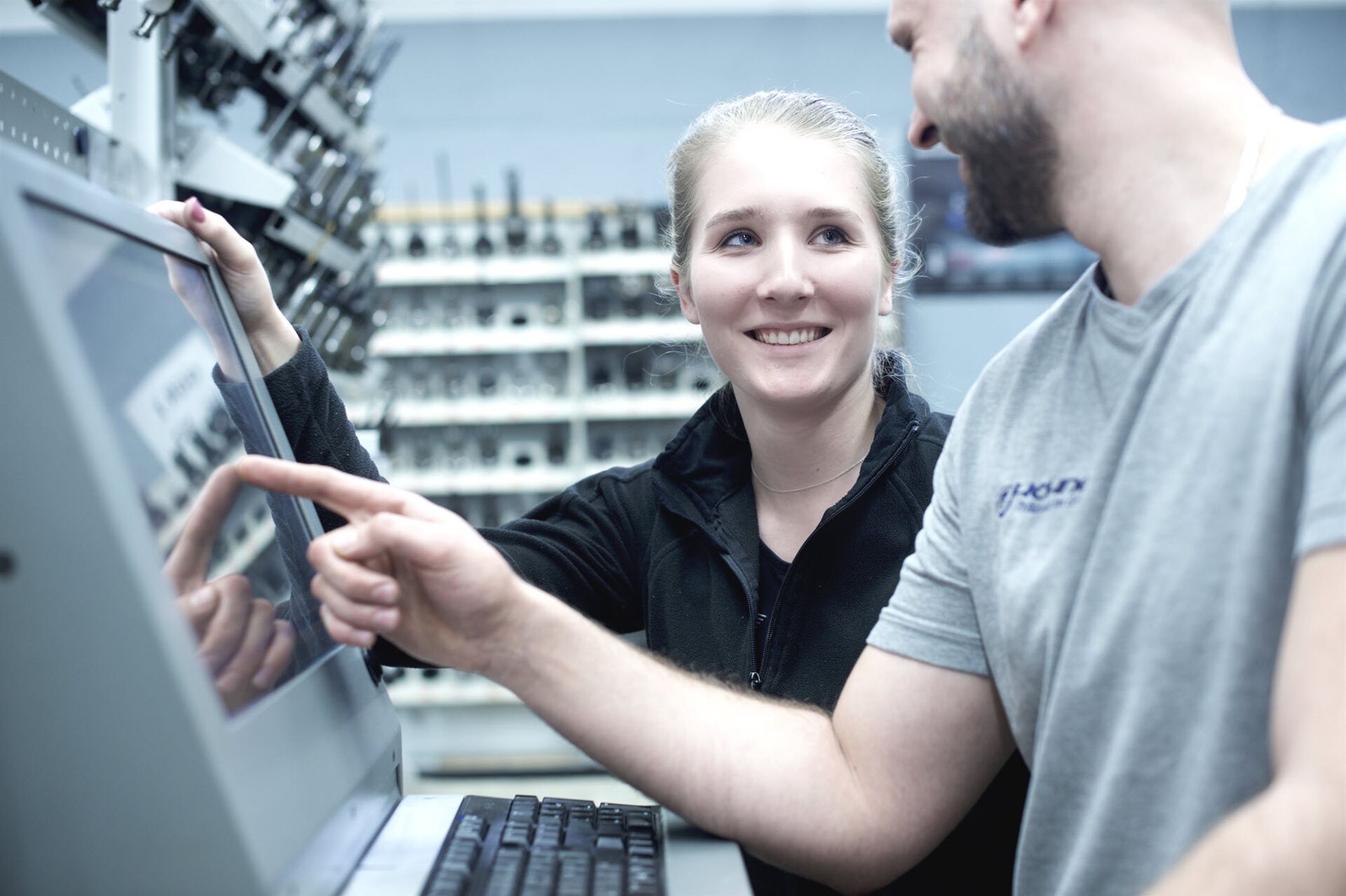 Zwei Mitarbeiter aus der Produktion unterhalten sich gut gelaunt vor einem PC-Terminal